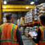 Male and female workers in hard hats collaborating in manufacturing warehouse using a tablet and customizing Dynamics 365 Business Central.
